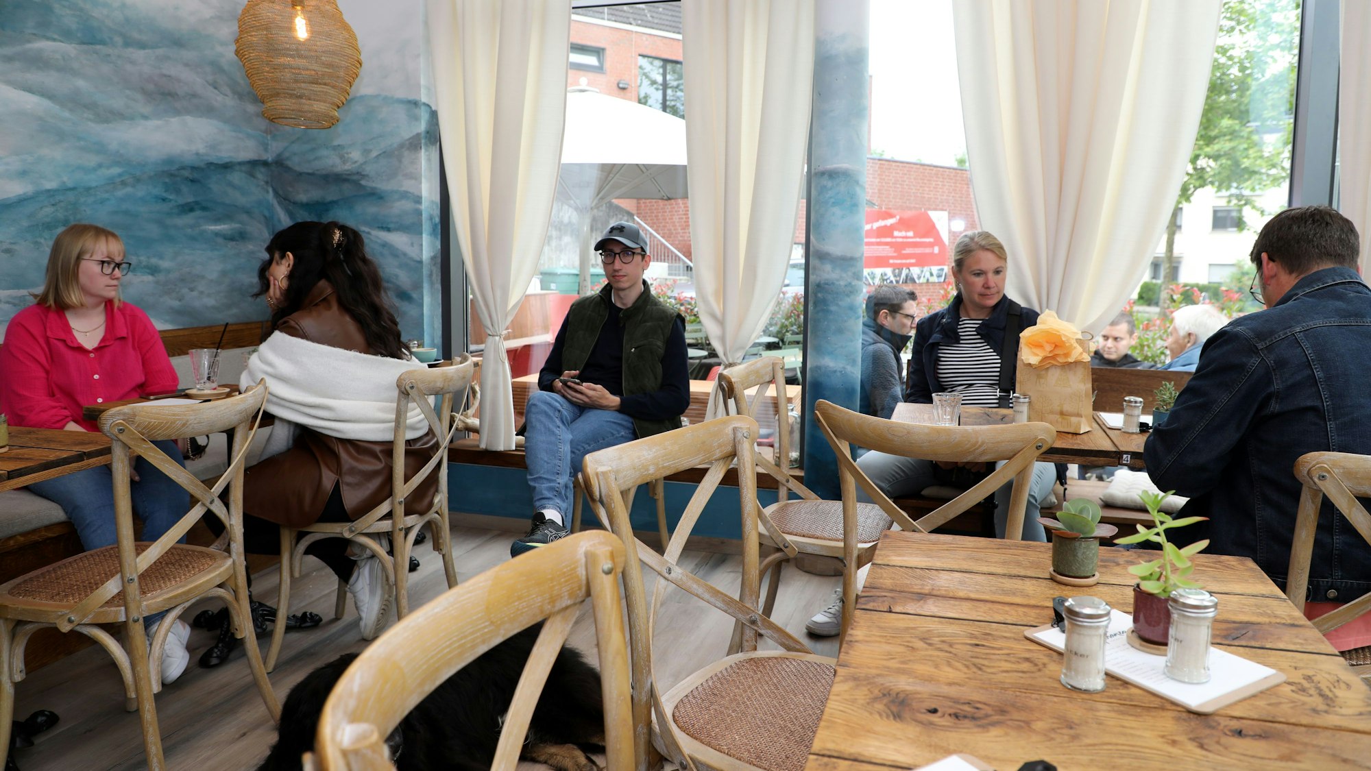 Gäste sitzen an Tischen im neu eröffneten Café Esperanza in Rösrath Forsbach.