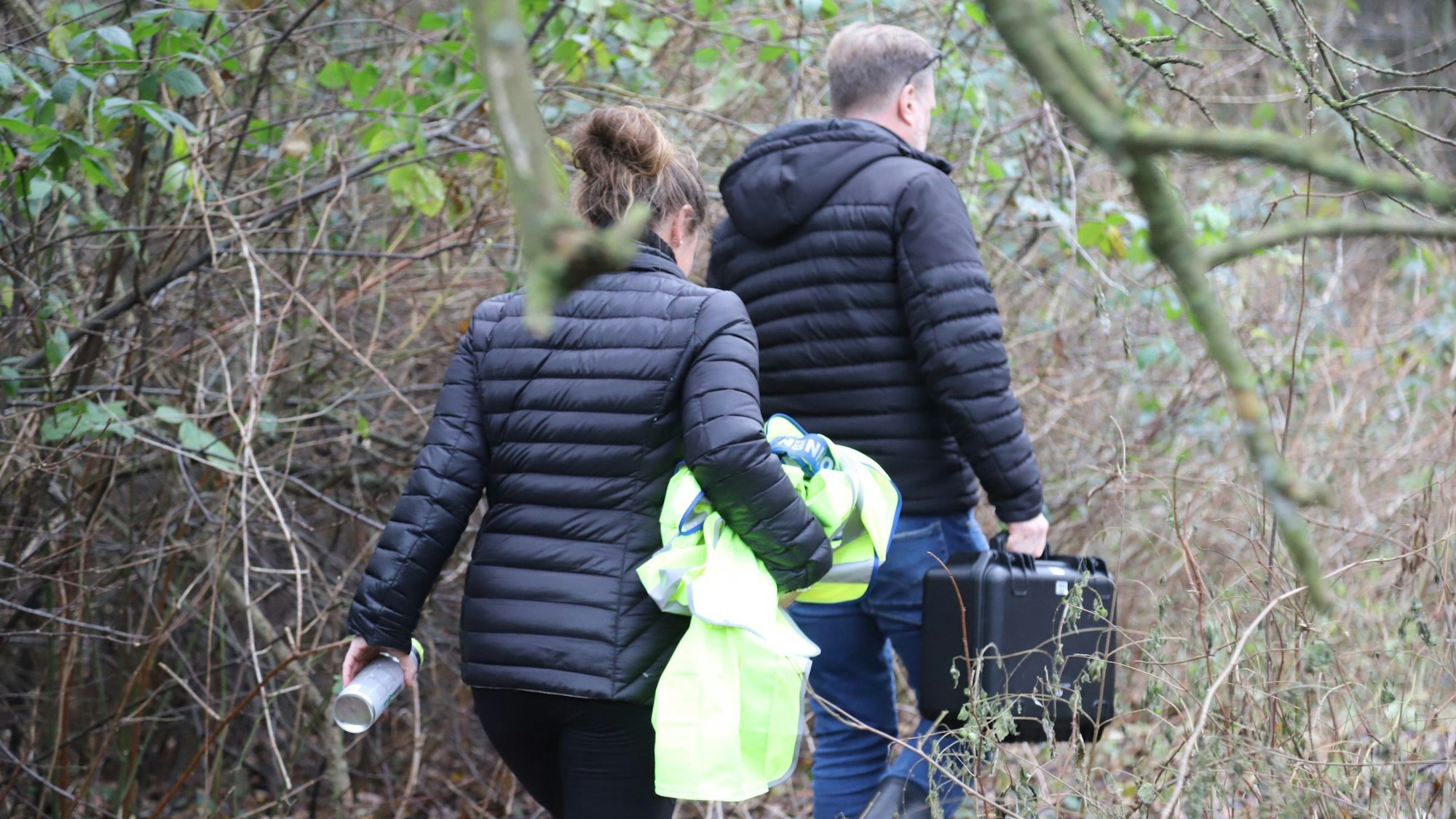 Beamte der Bielefelder Kriminalpolizei sind für die Spurensicherung auf dem Weg zu einer Waldfläche.