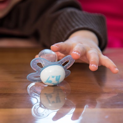 Ein Kleinkind greift nach einem Schnuller.