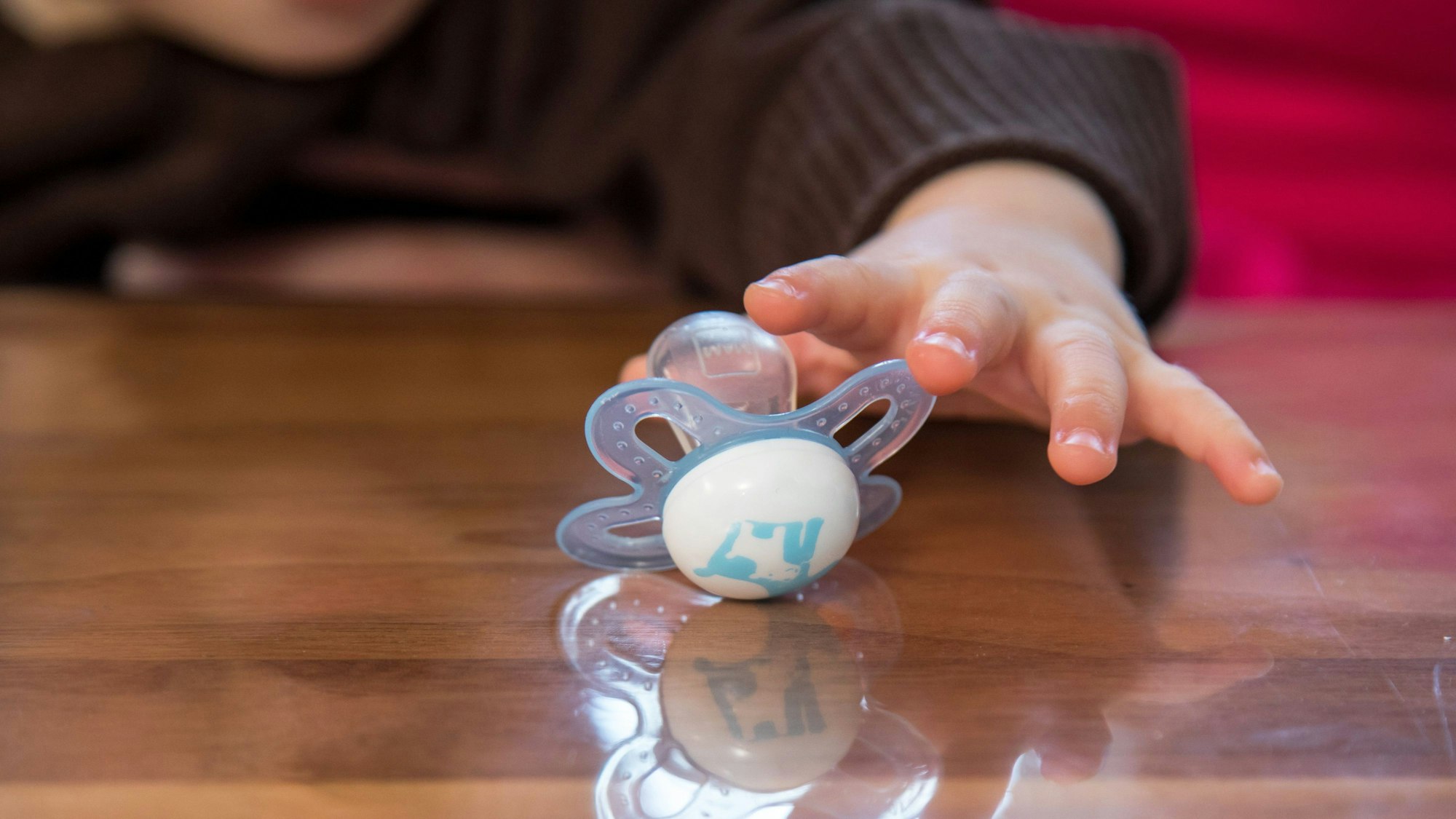 Ein Kleinkind greift nach einem Schnuller.