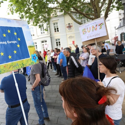 Menschen stehen auf einem Platz und halten Plakate mit der Europaflagge in die Höhe.