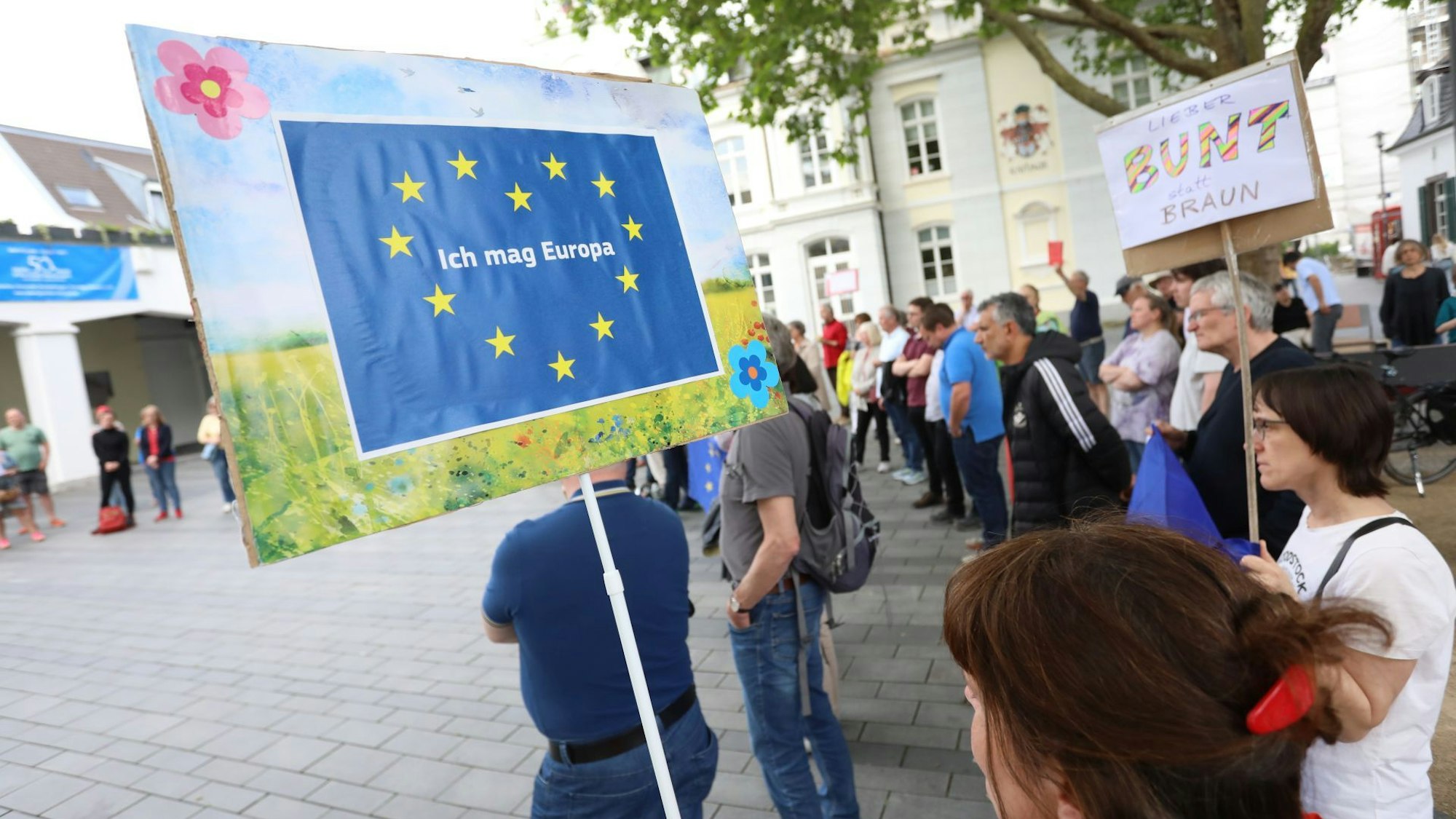 Menschen stehen auf einem Platz und halten Plakate mit der Europaflagge in die Höhe.
