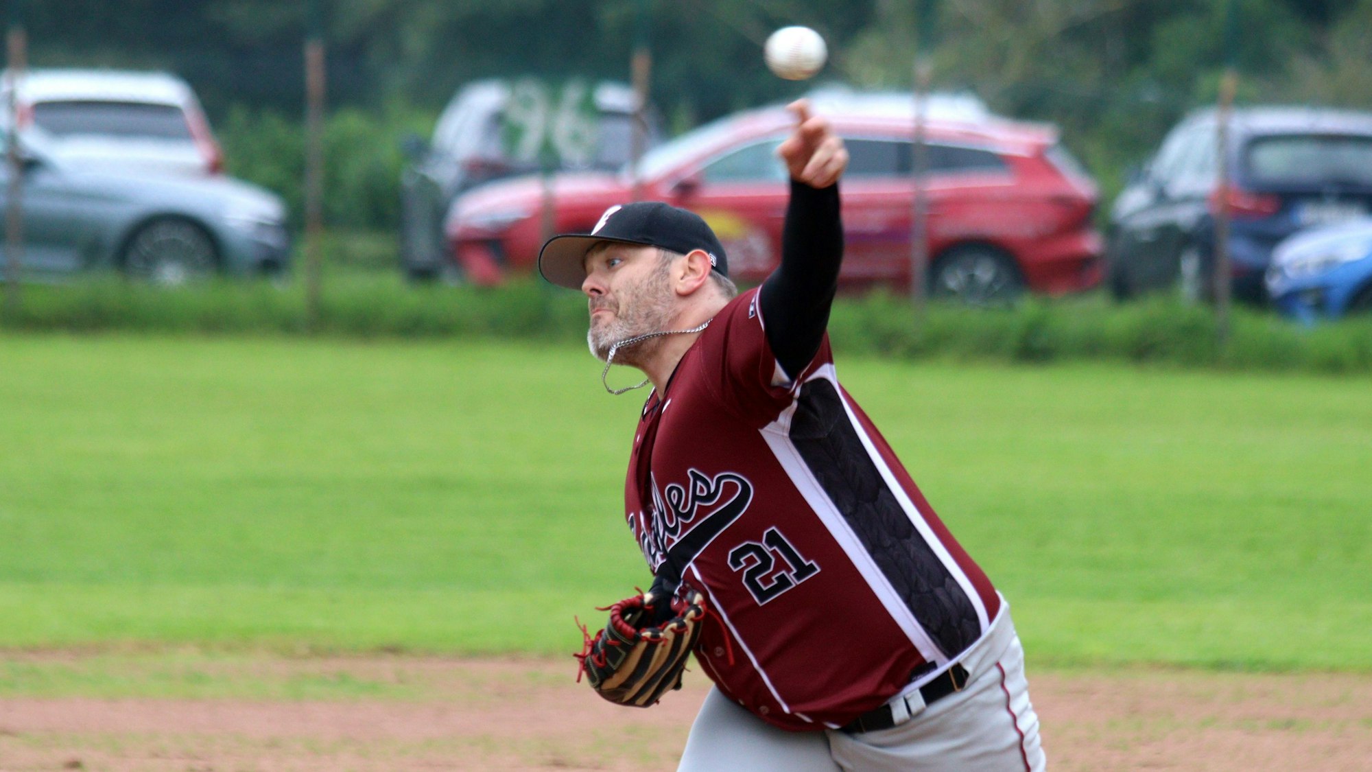 Ein Pitcher wirft einen Baseball. Seine Halskette schlägt ihm ans Kinn.