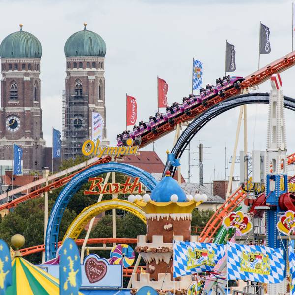 Bayern, München: Oktoberfestbesucher fahren 2018 in einer Achterbahn auf dem Oktoberfest auf der Theresienwiese. Im Hintergrund ist die Frauenkirche in der Münchner Altstadt zu sehen.