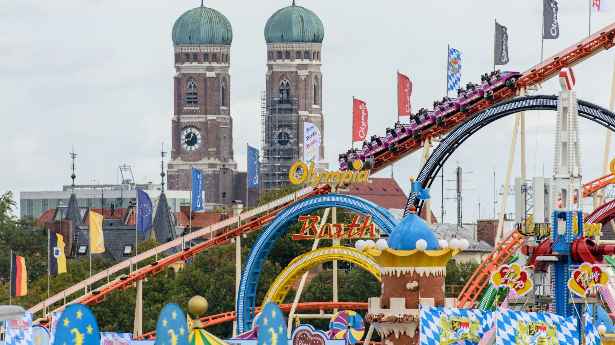 Bayern, München: Oktoberfestbesucher fahren 2018 in einer Achterbahn auf dem Oktoberfest auf der Theresienwiese. Im Hintergrund ist die Frauenkirche in der Münchner Altstadt zu sehen.