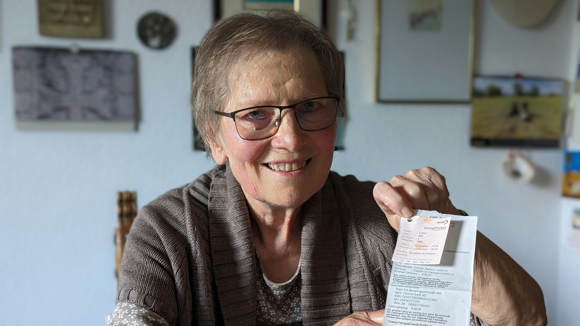 Eine Frau hält einen Busfahrschein und den Ausdruck einer Zahlungsaufforderung in den Händen.
