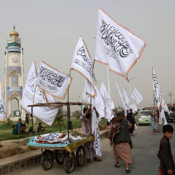 Ein afghanischer Mann und Kinder verkaufen während einer Feier zum zweiten Jahrestag des Abzugs der US-amerikanischen Truppen aus Afghanistan Taliban-Fahnen an Passanten.
