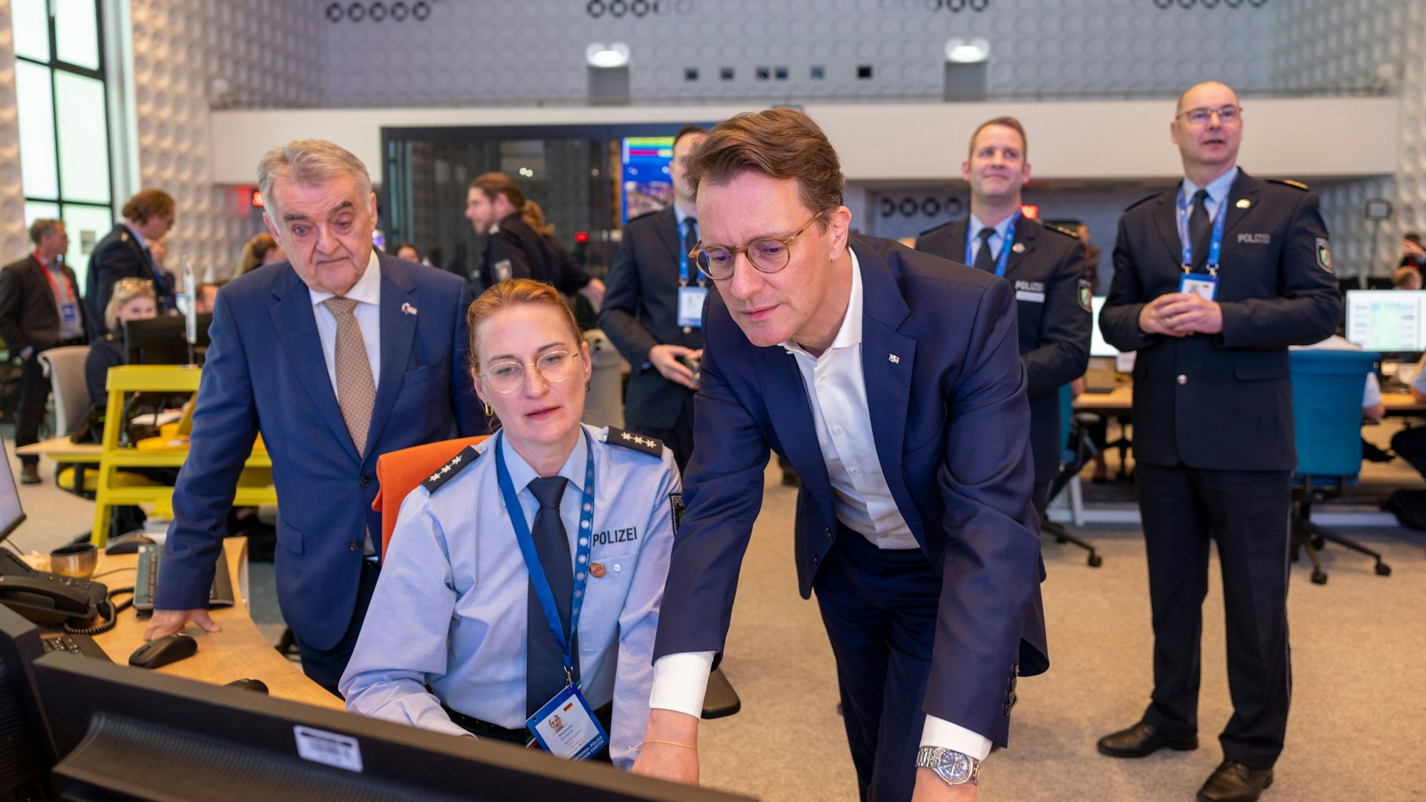 Hendrik Wüst (CDU, r), Ministerpräsident von Nordrhein-Westfalen, und Herbert Reul (CDU, l), Innenminister des Landes Nordrhein-Westfalen, informieren sich bei einer Polizeibeamtin vor Beginn der Fußball-EM im Informationszentrum der Polizei (IPCC).