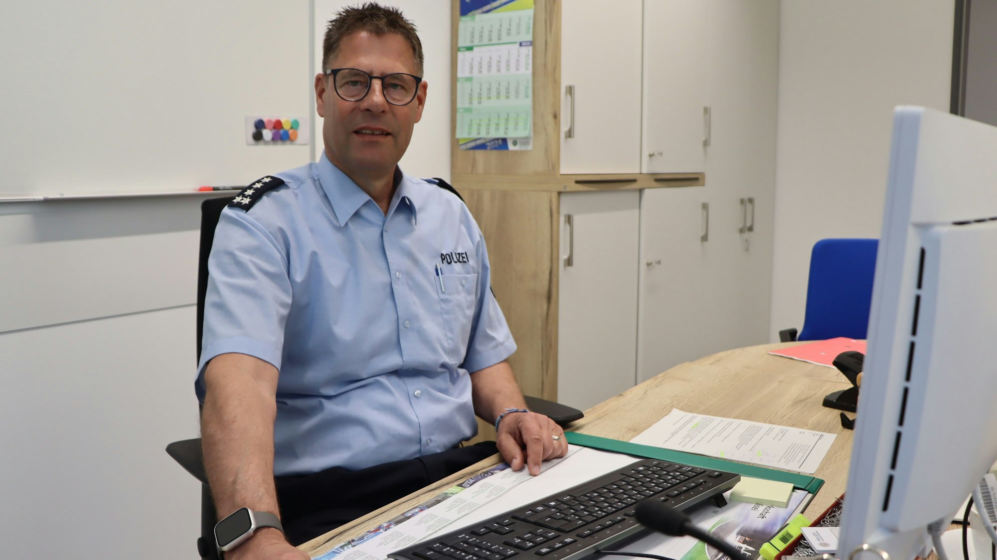 Auf dem Foto ist der Polizeibeamte Uwe Bellmann an seinem Schreibtisch zu sehen.