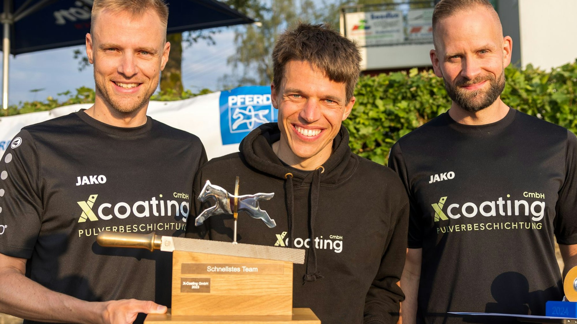 Bild dreier Läufer mit Trophäe