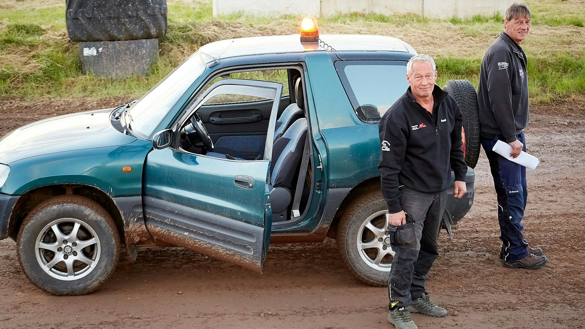 Axel Ganescu und Rudolf Linden (rechts) stehen am türkisblauen Safety-Car der Westdeutschen Auto-Cross-Meisterschaften in Blankenheim-Waldorf.