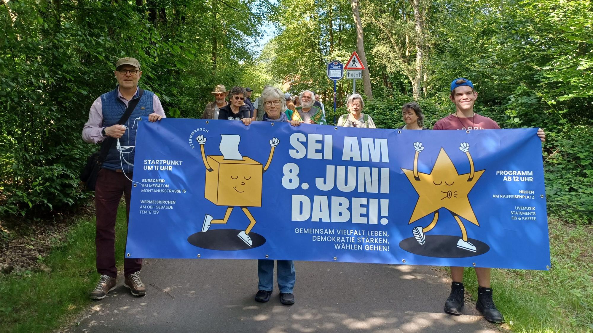 Menschen mit einem Banner gehen auf der Balkantrasse.