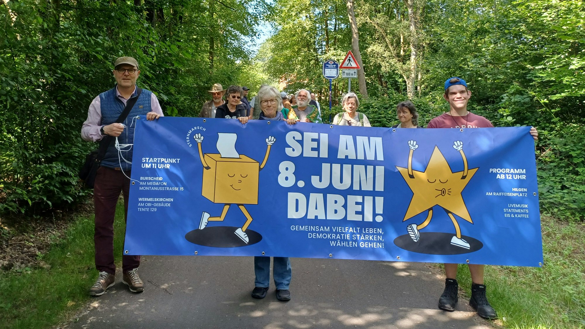 Menschen mit einem Banner gehen auf der Balkantrasse.