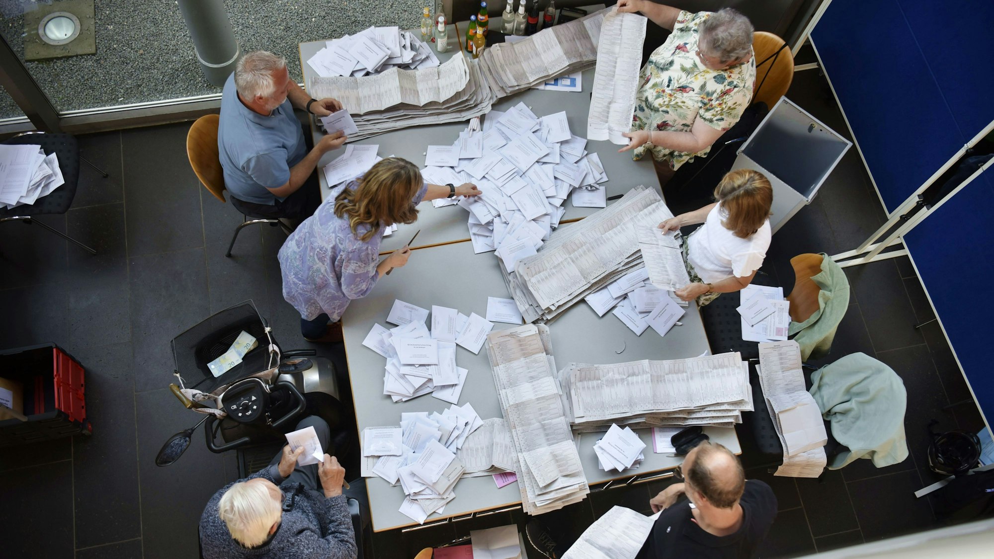 Wahlhelfer zählen die Stimmen, der Tisch ist voller Stimmzettel.