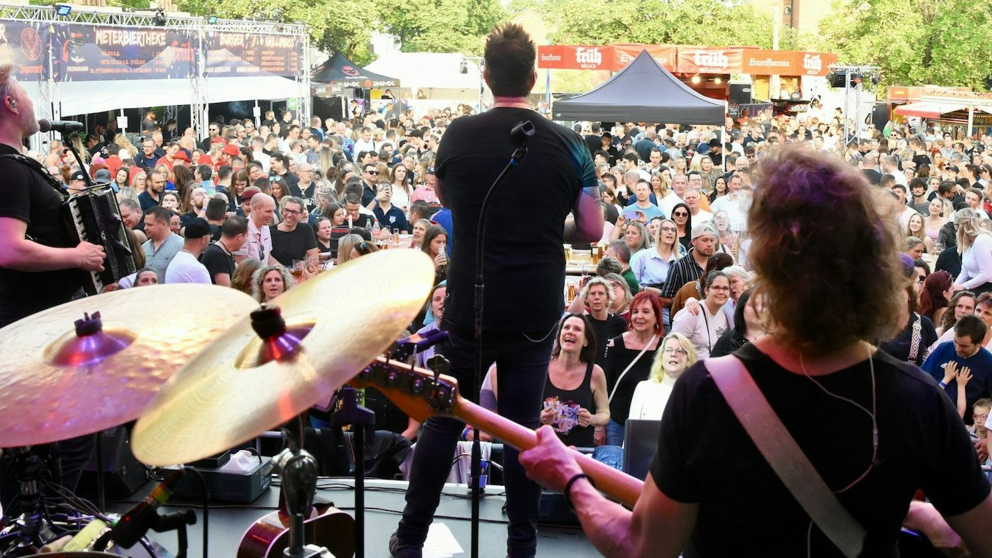 Eine Band steht auf der Bühne, vor der viele hundert menschen dicht gedrängt stehen.