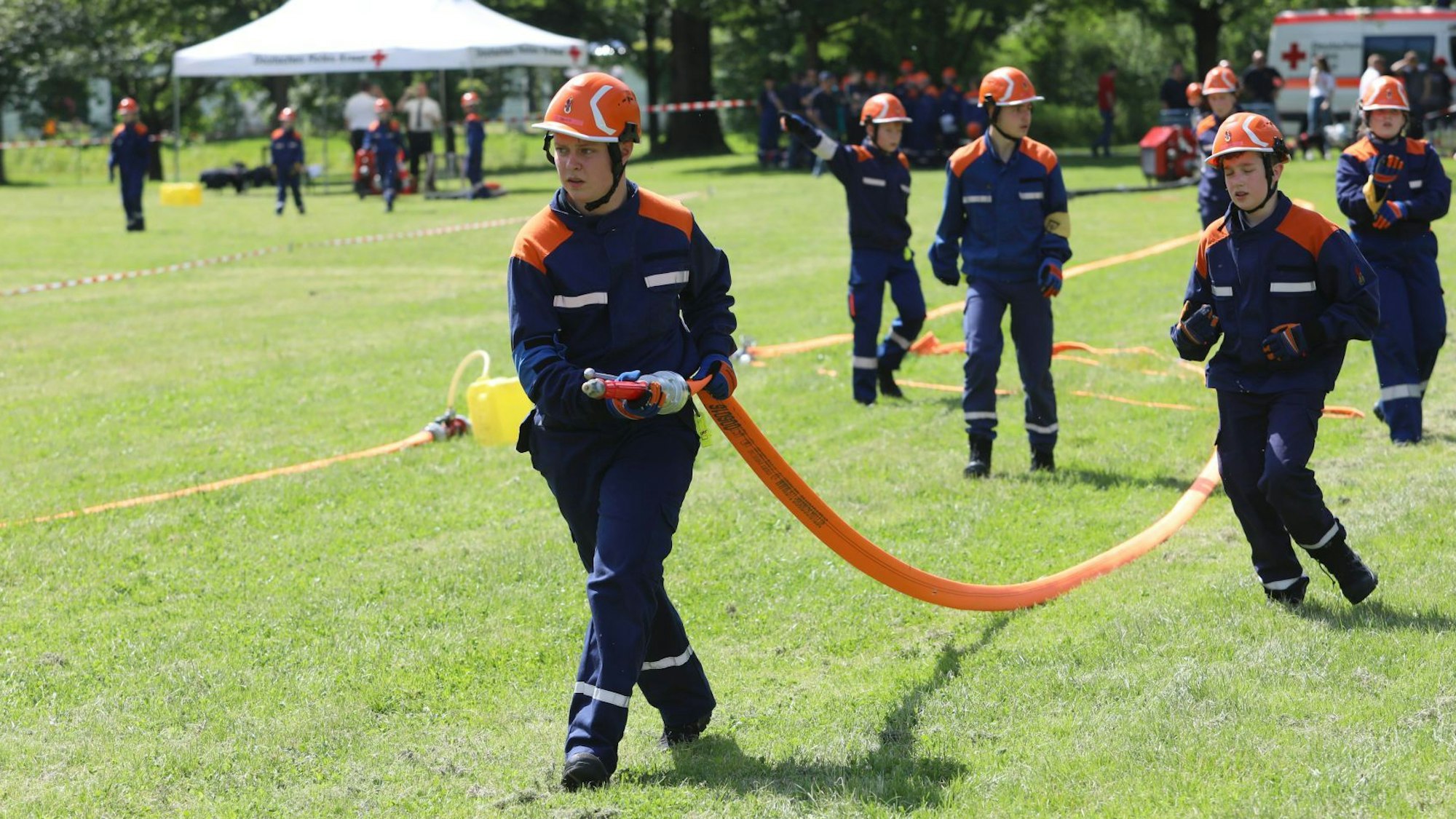 Junge Feuerwehrleute tragen einen Schlauch