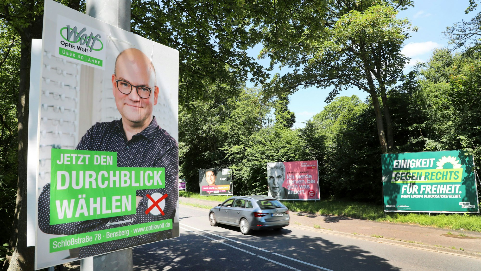 Neben Plakaten von Parteien zur Europawahl hängt ein der Wahlwerbung nachempfundenes Plakat eines Optikers, der für „Jetzt Durchblick wählen“ wirbt.