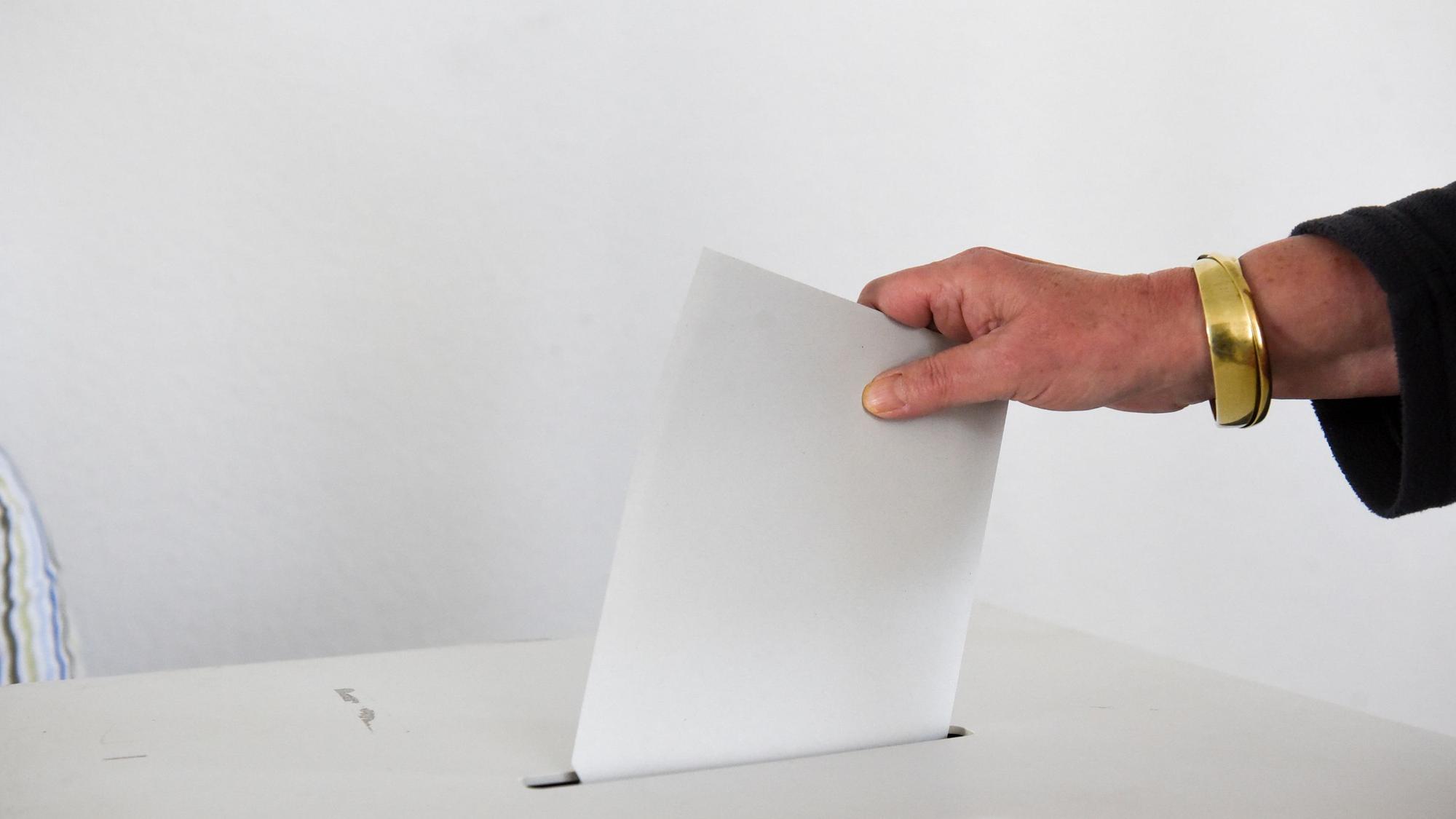 Auf dem Foto ist zu sehen, wie eine Frau ihren Stimmzettel in die Wahlurne wirft.