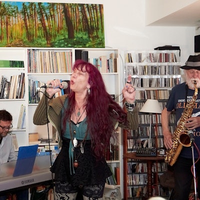 Sängerin Simone Reifegerste steht in der Bildmitte, sie hält ein Mikrofon in der Hand und singt. Rechts von ihr ist ein Mann zu sehen, der Saxofon spielt, links litzt ein Musiker an einem Keyboard.