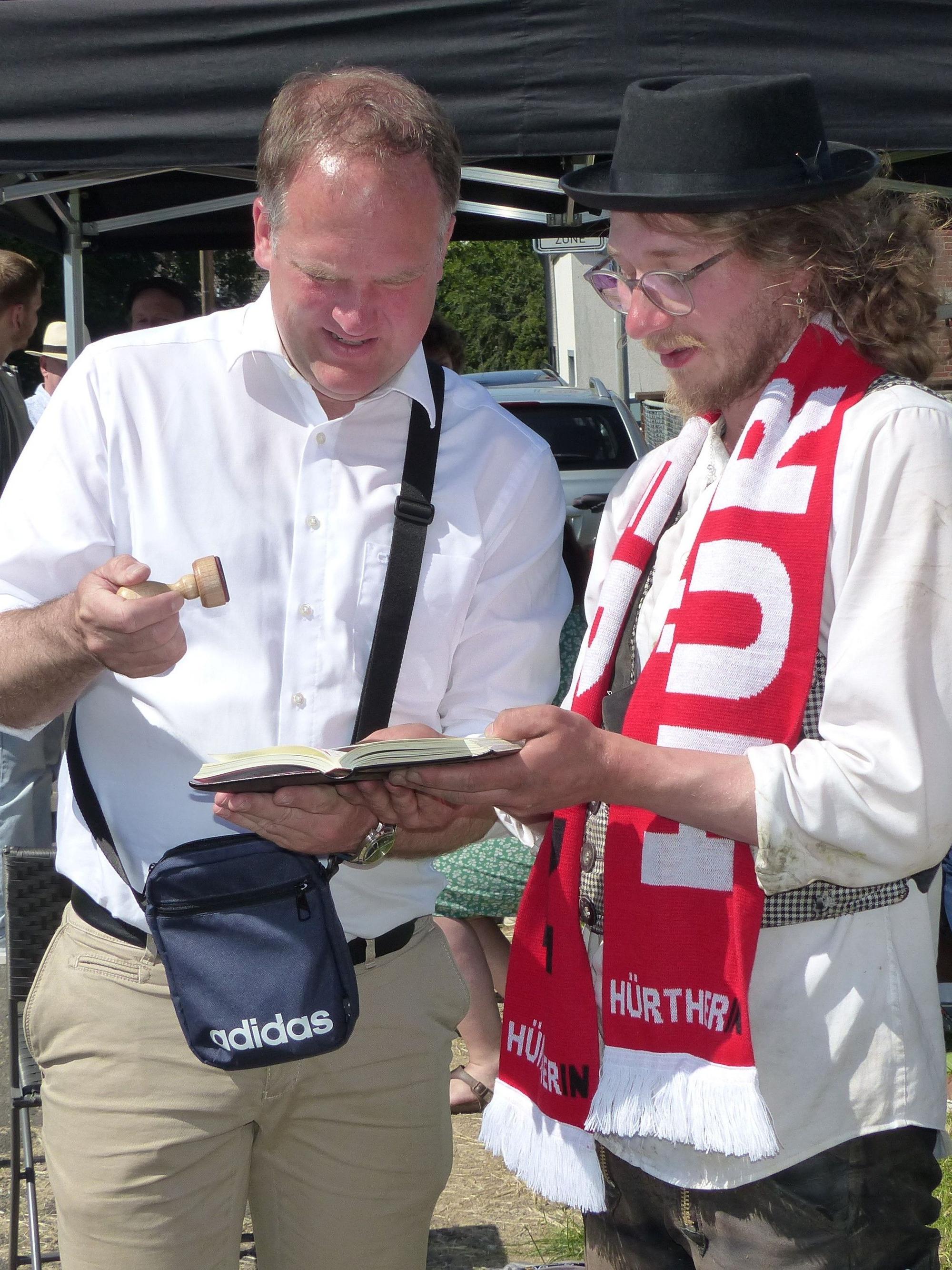 Bürgermeister Dirk Breuer drückt dem Walz-Heimkehrer Moritz David das Stadtsiegel ins Wanderbuch.