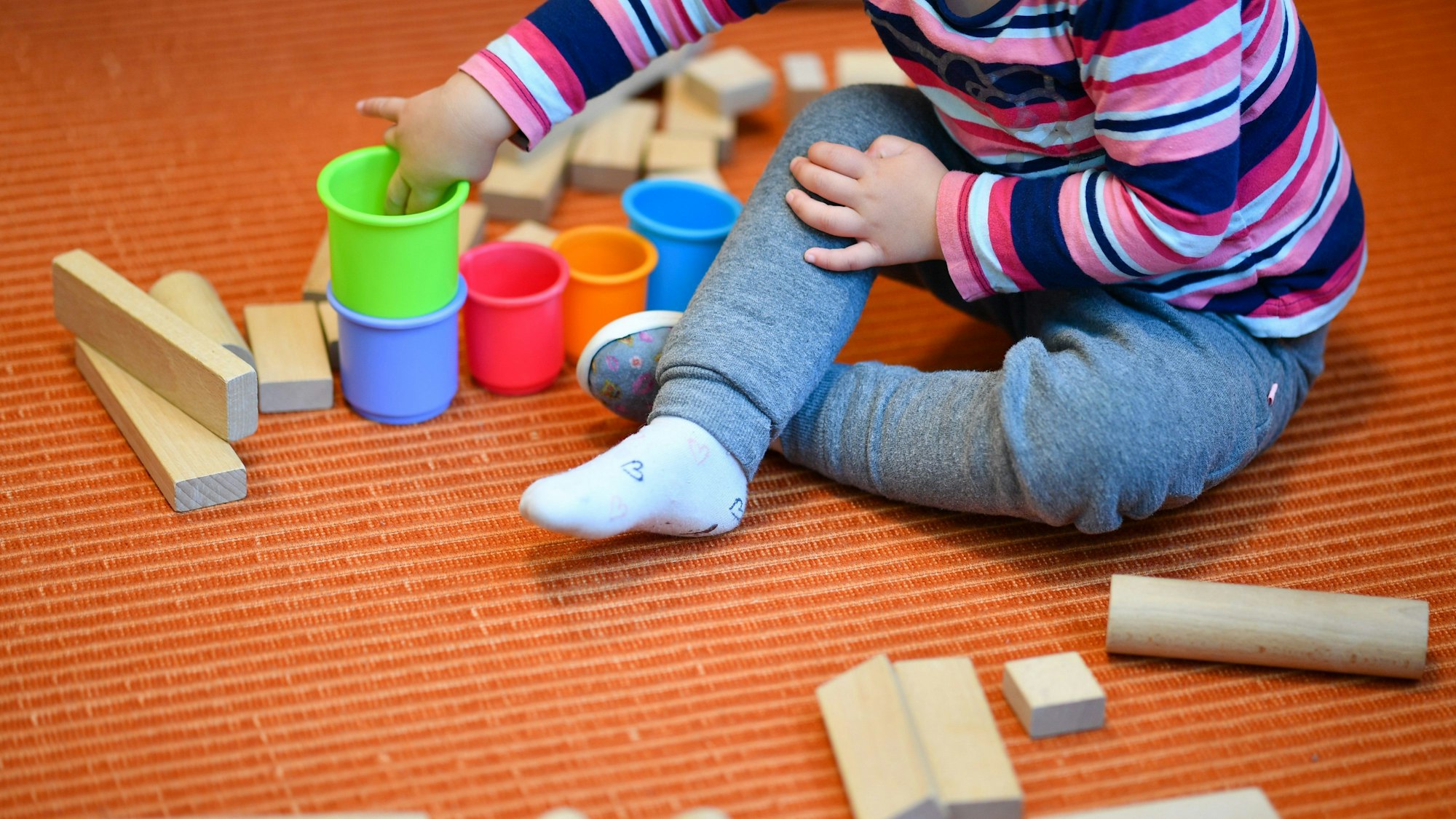 Ein Mädchen spielt in einer Kita mit bunten Bechern und Bauklötzen.(Symbolbild)dpa