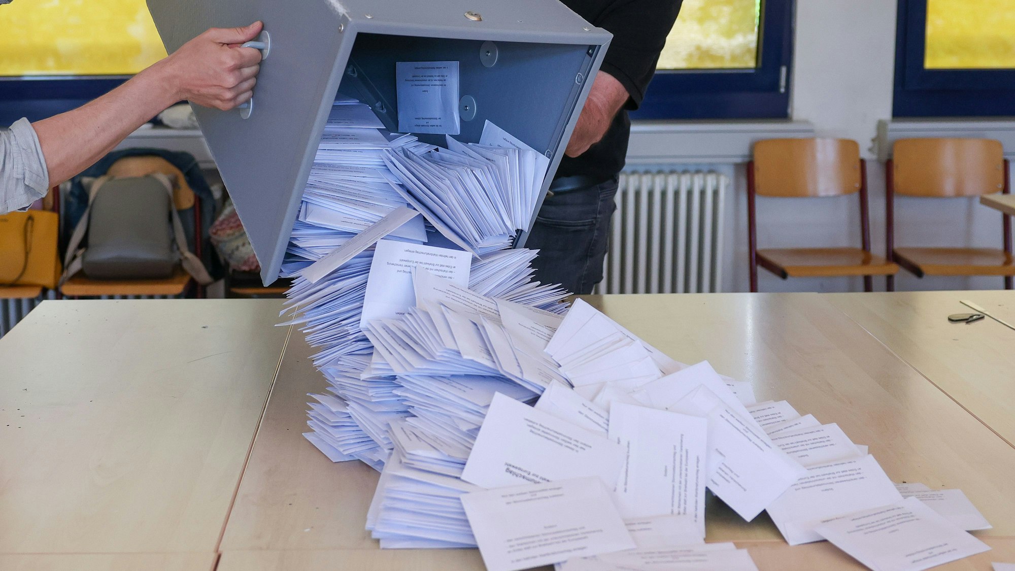 Zwei Wahlhelfer kippen eine Wahlurne mit den Briefwahlstimmen nach der Europawahl in einem Briefwahllokal zur Stimmenauszählung auf einen Tisch.