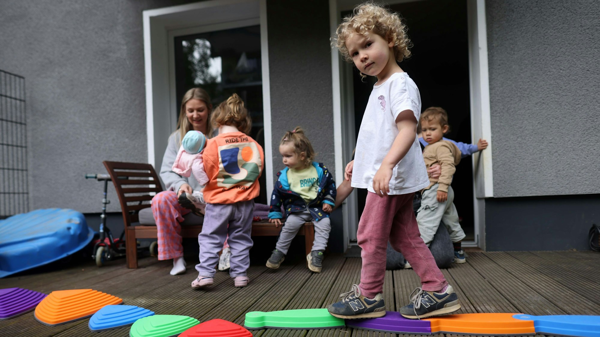 Ein Kind balanciert über eine bunte Plastikschlange.