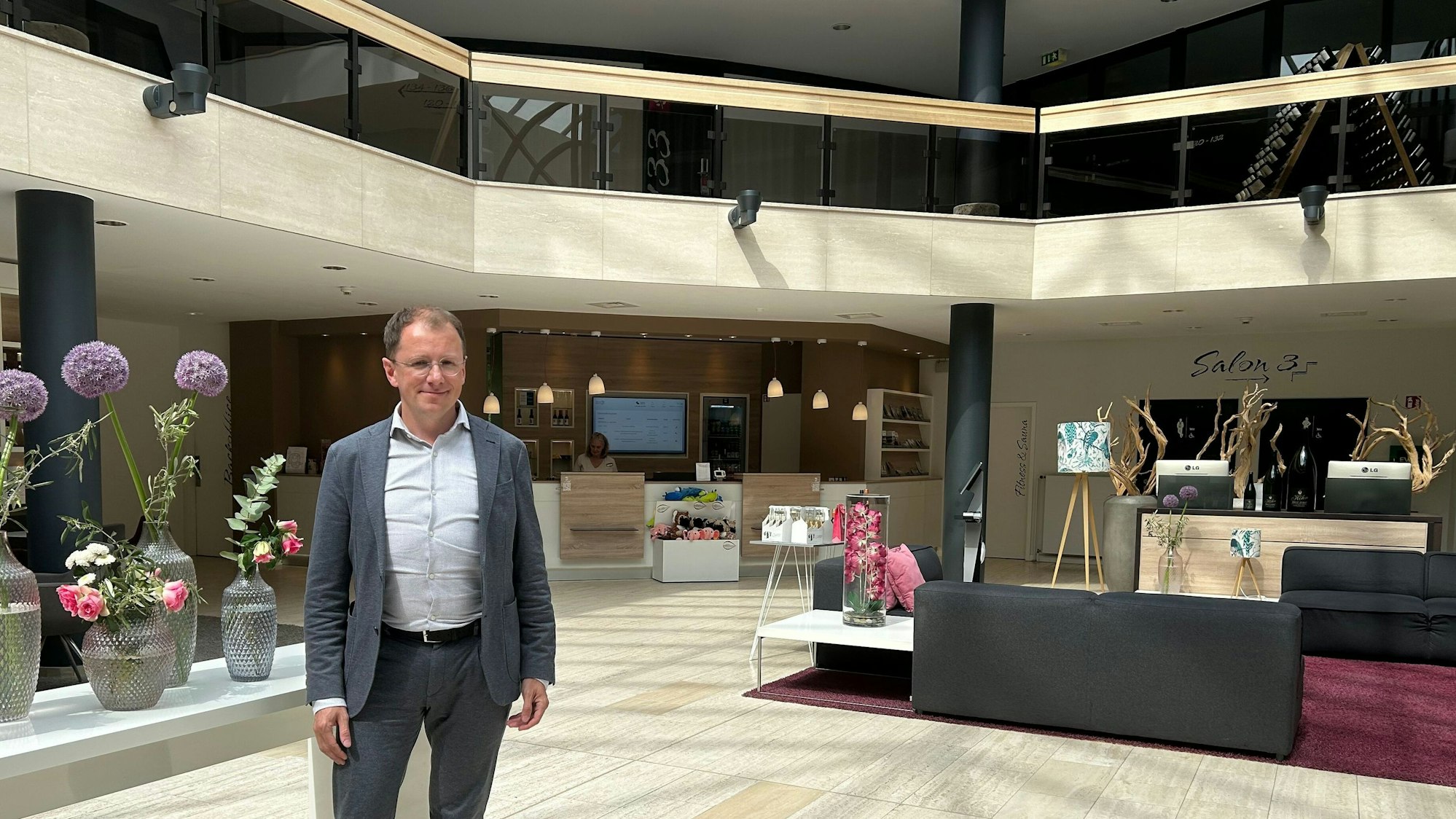 Peter Gebhardt, Geschäftsführer Best Western Plus Parkhotel Velbert, steht in einem grauen Anzug in der Lobby des Parkhotel Velbert.