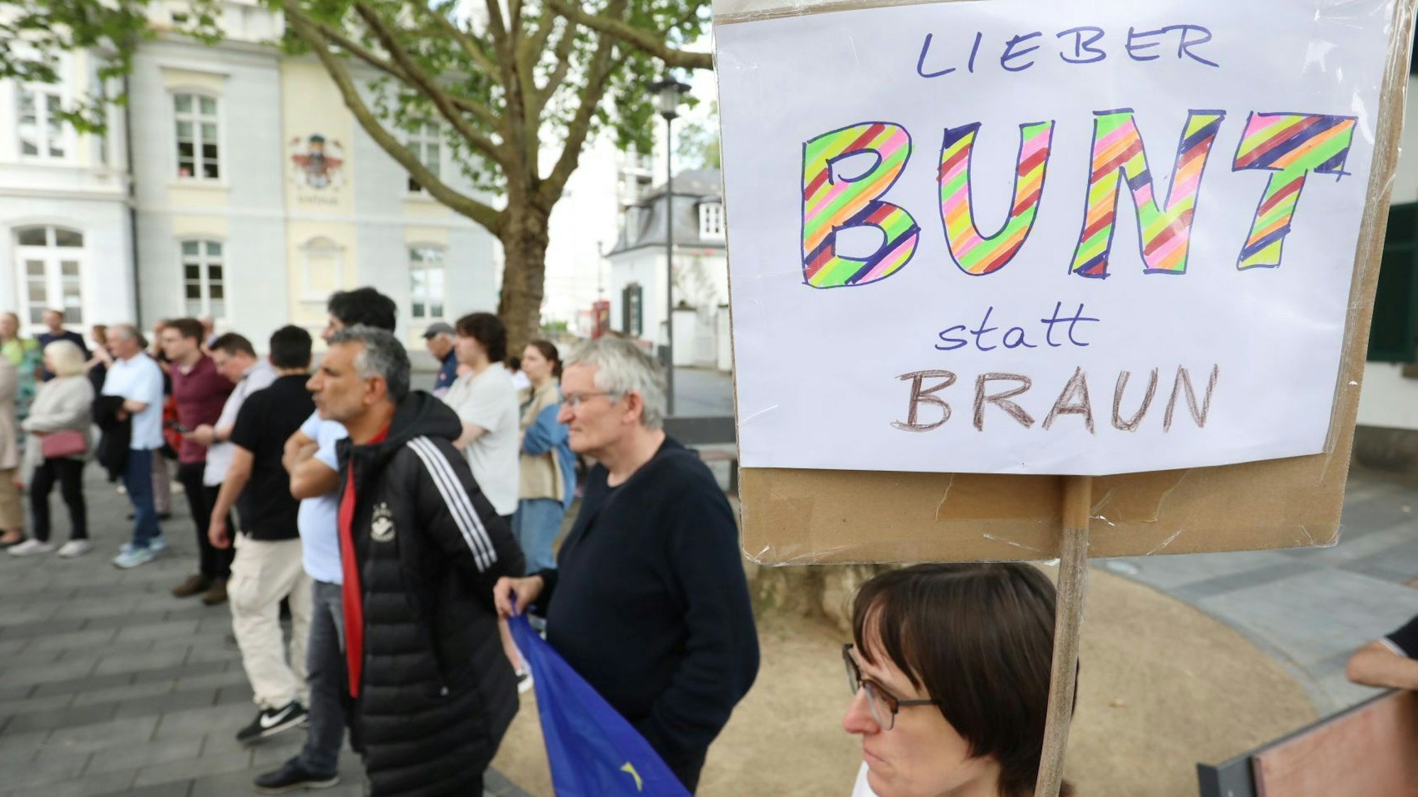 Eine Gruppe von Menschen bei einer Kundgebung, im Vordergrund ein Schild mit der Aufschrift "Liebe bunt statt braun".