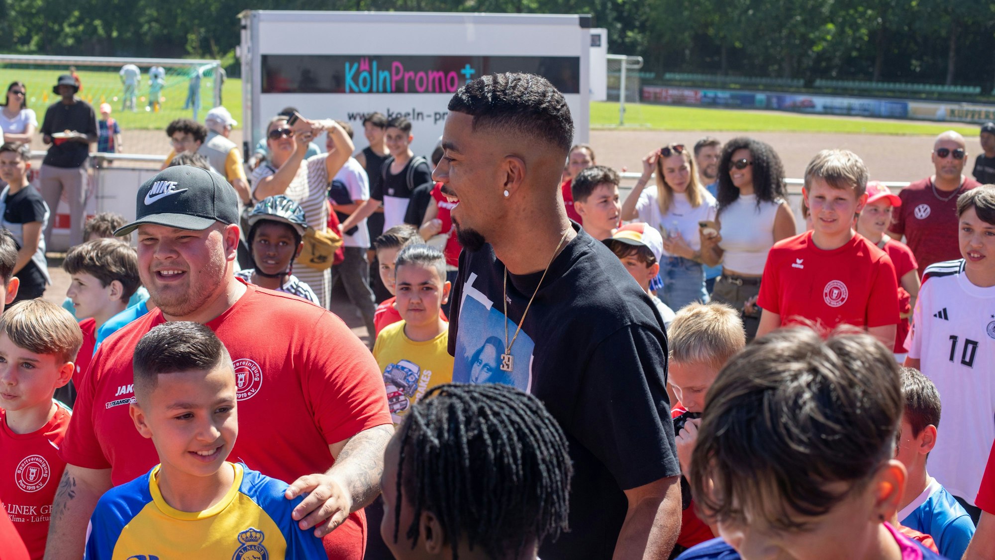 Fußball-Nationalspieler Benjamin Henrichs wird bei seiner Ankunft auf dem Sommerfest der Sportvereinigung Porz von jungen Kickern umringt.