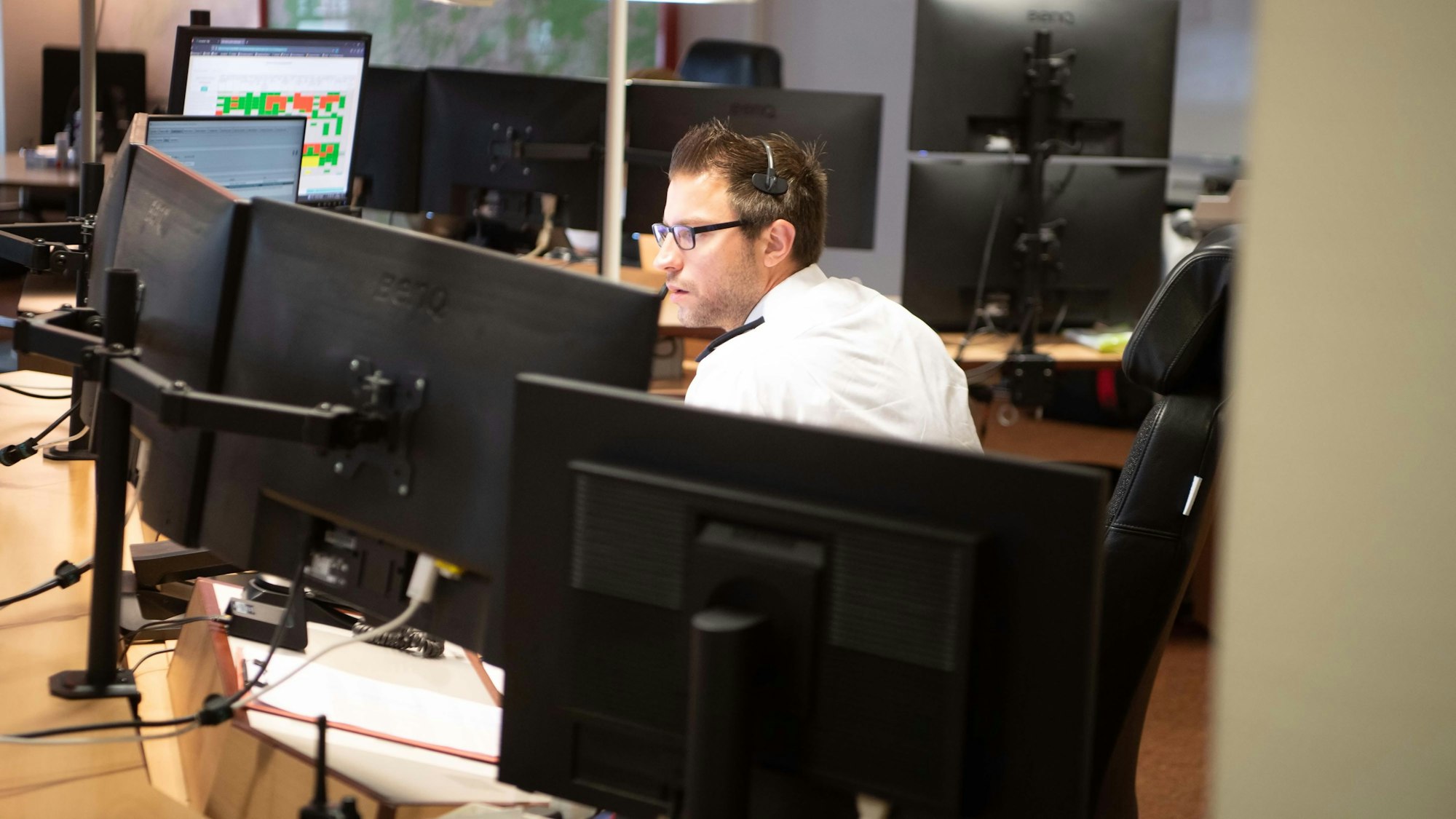 Das Bild zeigt einen Disponenten hinter zahlreichen Bildschirmen in der Leitstelle.