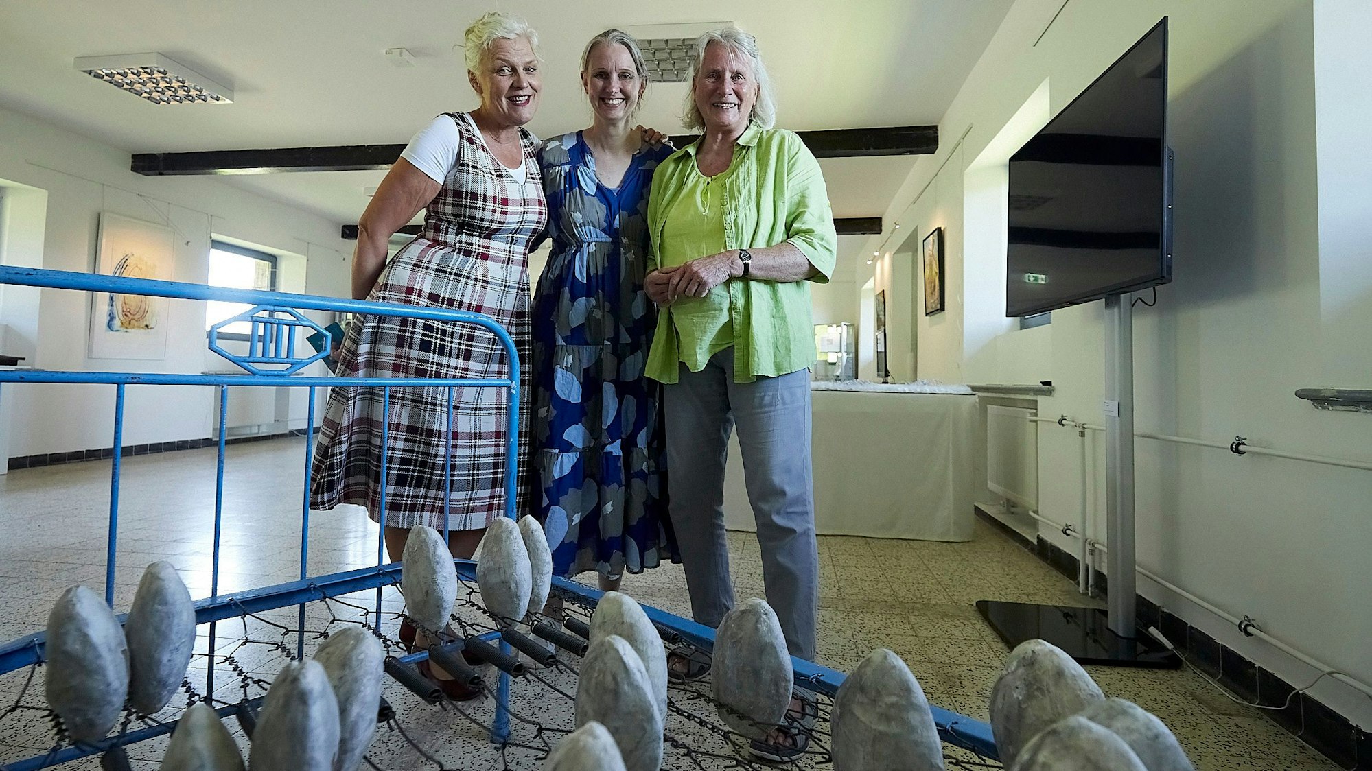 Barbara Geiger, Sabine Heilmann und Maria Pfeifer stehen nebeneinander, davor sieht man ein Bettgestell mit muschelartigen Objekten.