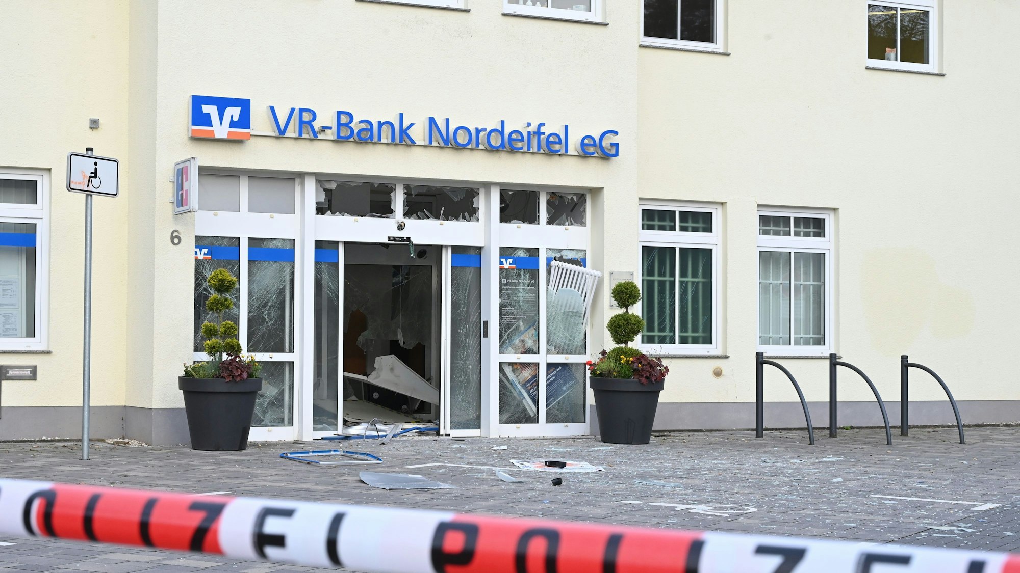 Vor dem Gebäude mit dem blauen Schriftzug der VR-Bank liegen Splitter, ein rot-weißes Band mit der Aufschrift Polizei sperrt den Tatort ab.