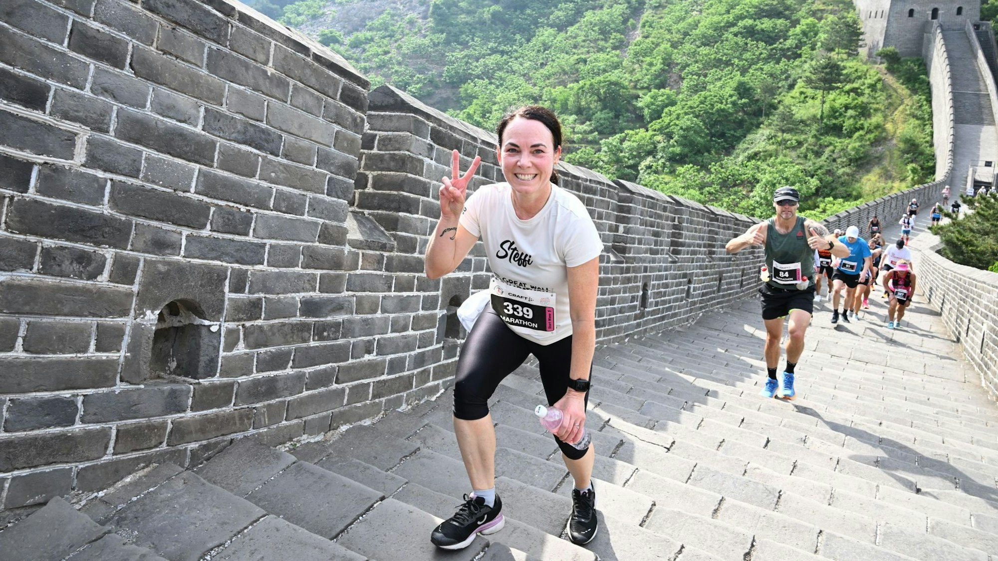 Stefanie Bart steht auf der Chinesischen Mauer und macht mit zwei Fingern das „Peace-Zeichen“.