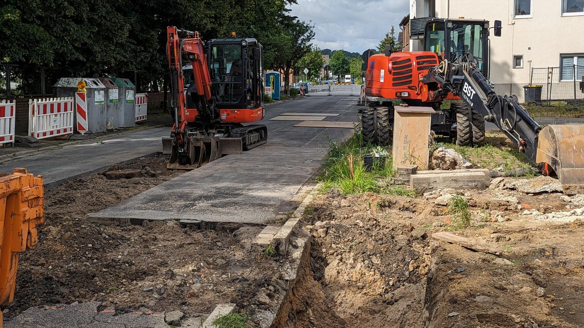 Das Foto zeigt zwei Bagger vor Baugruben an einer abgesperrten Straße.
