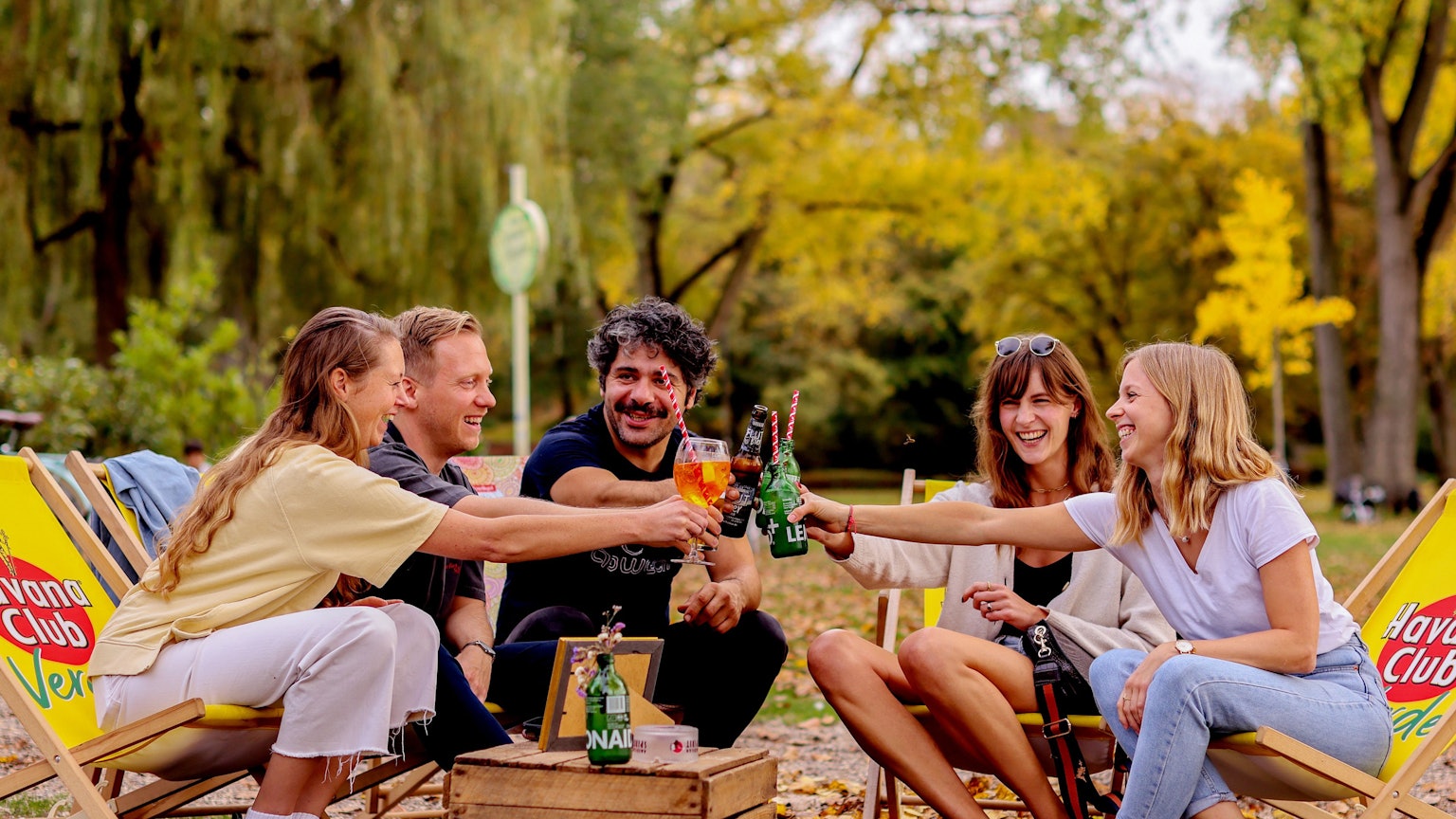 Junge Leute sitzen bei sonnigem und warmen Herbstwetter im Biergarten am Aachener Weiher in Köln.