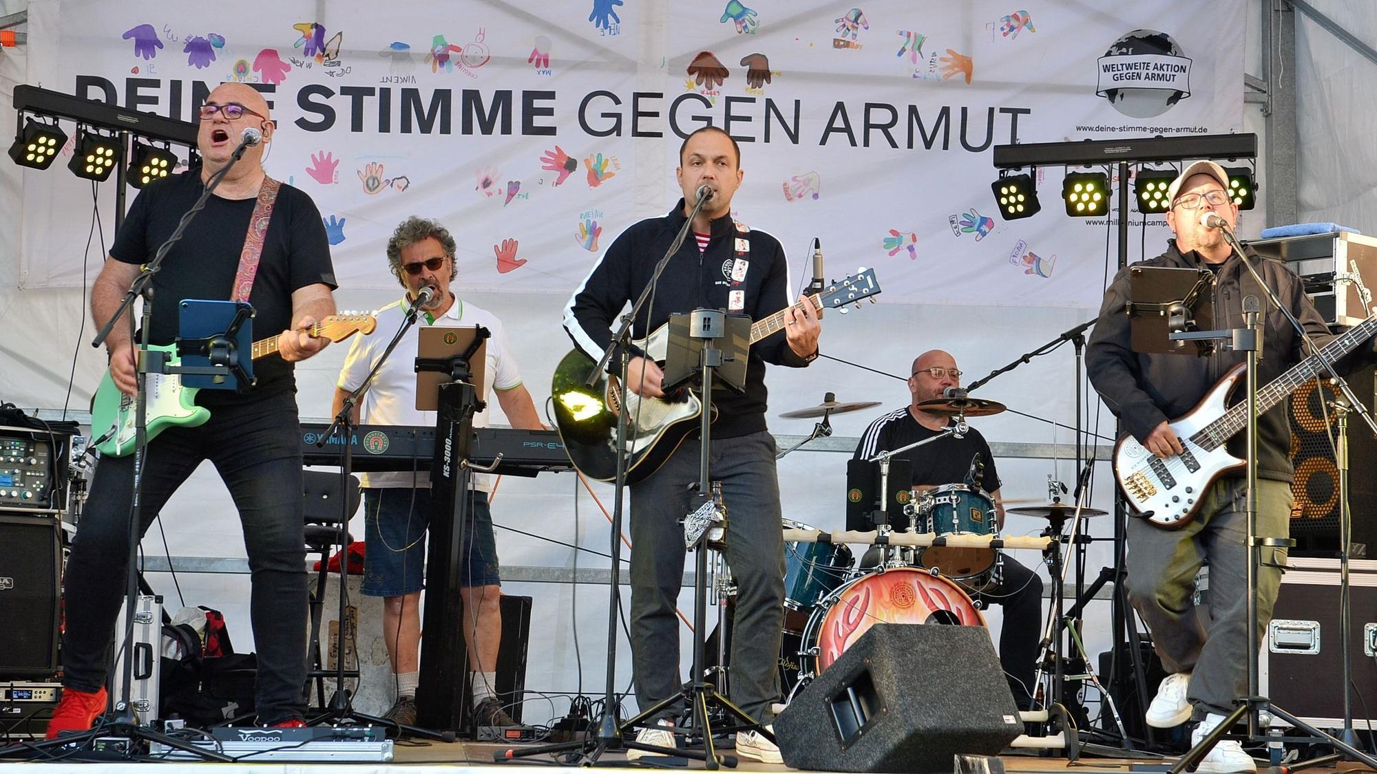 Die Musiker der Band „Wömbe Jonge“ stehen auf der Bühne und spielen ihre Instrumente.