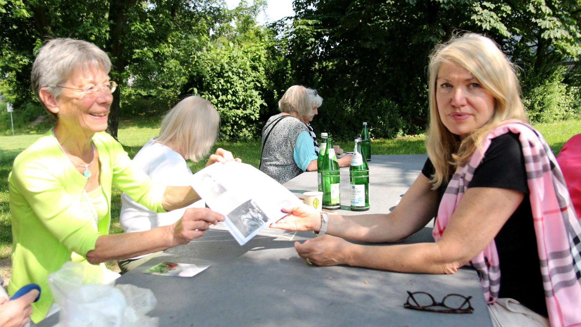 Zwei Frauen sitzen an einem Tisch, sie halten ein Blatt in der Hand.