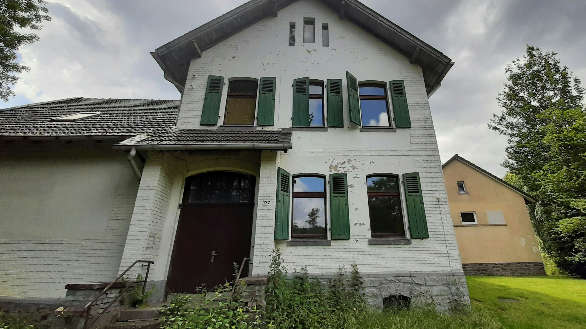 Ein weißer Altbau mit grünen Fensterläden.