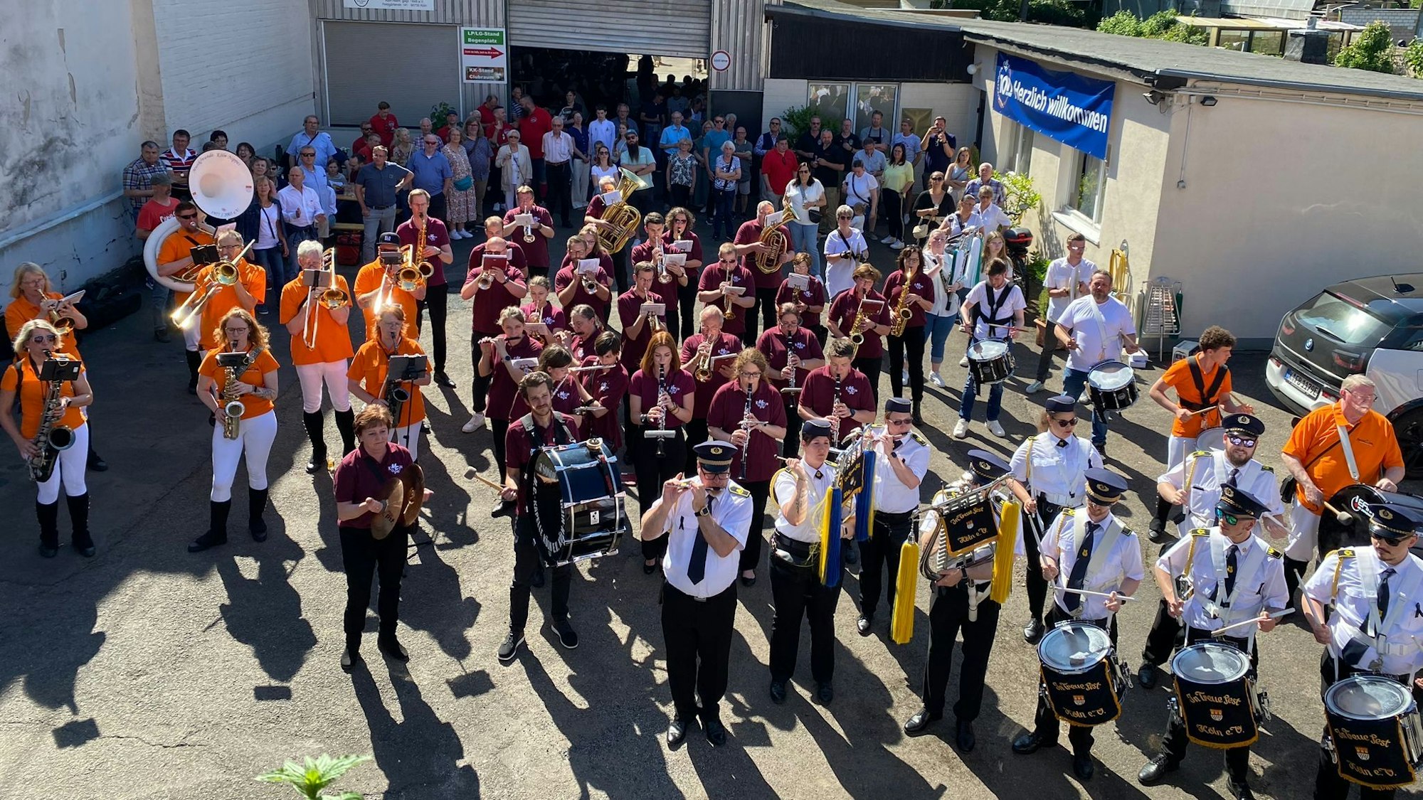 Blick auf verschiedene Musikgruppen in unterschiedlichen Uniformen und mit Trommeln, Blasinstrumenten und Zuschauern