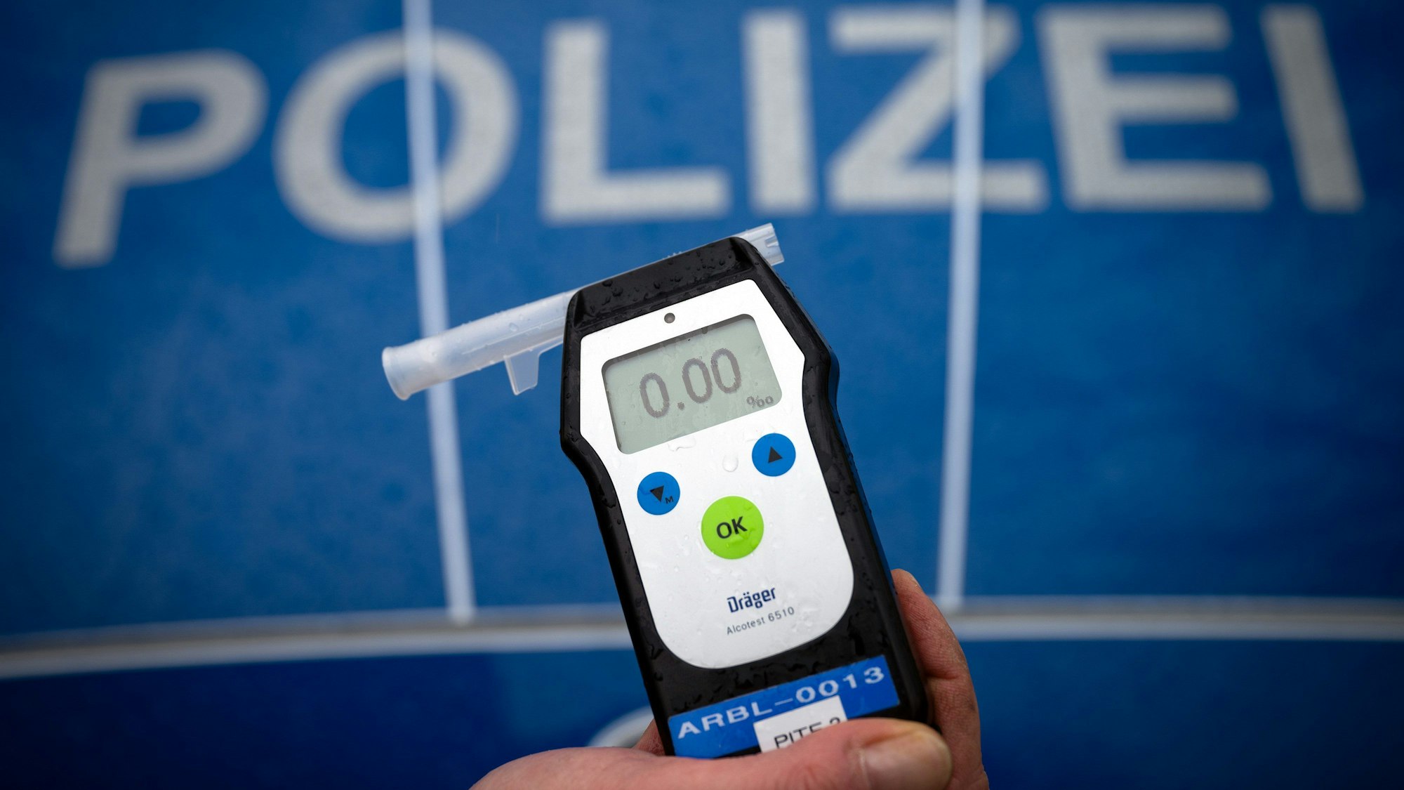 Ein Polizeibeamter hält während einer Verkehrskontrolle ein Messgerät Alcotest.