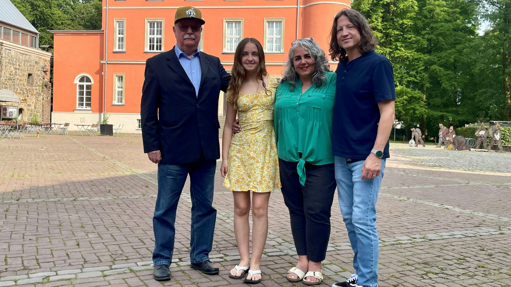 Zwei Männer und zwei Frauen vor einem alten Herrenhaus.