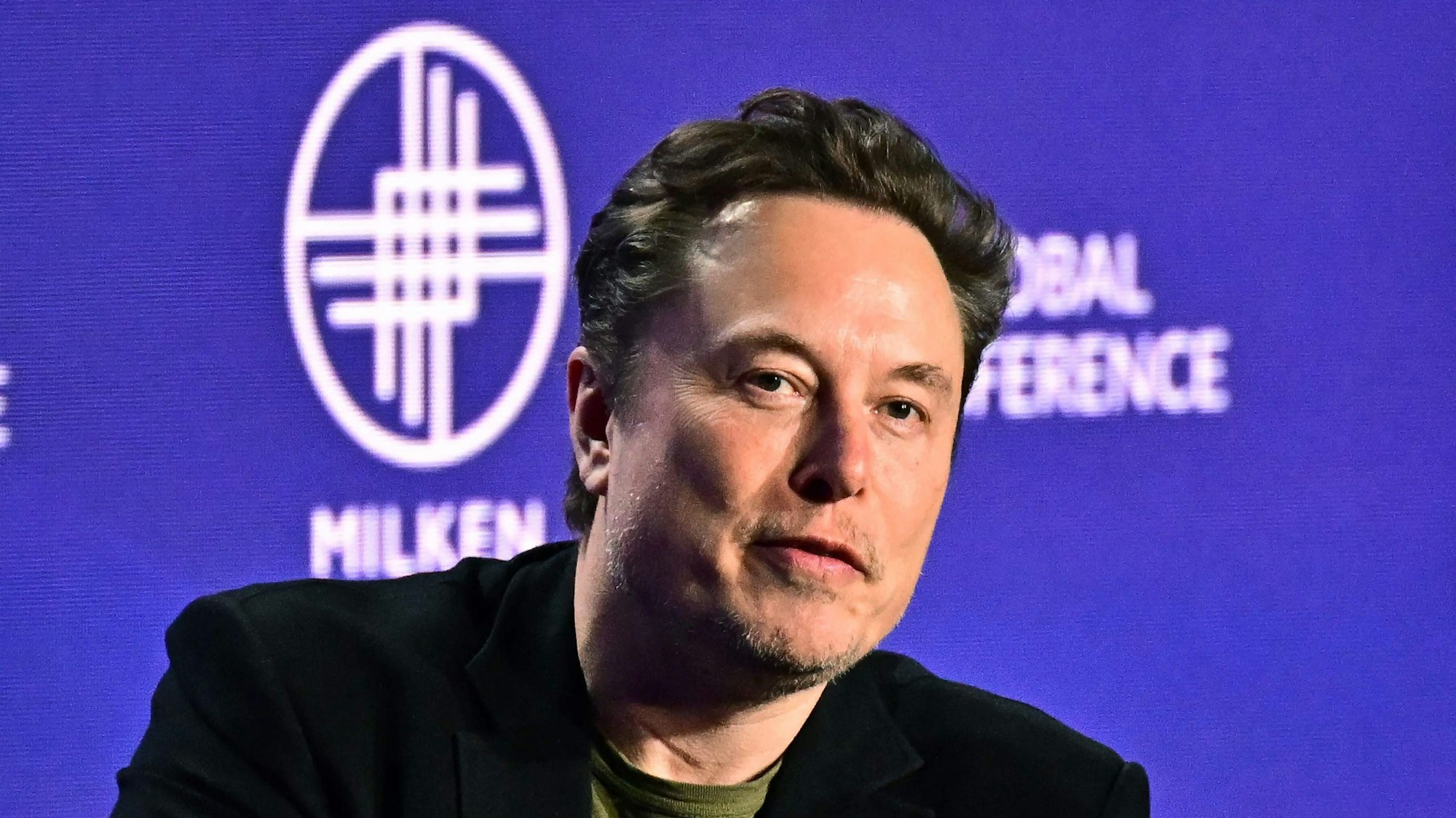 Tesla CEO Elon Musk spricht bei einer Konferenz auf einer Bühne.