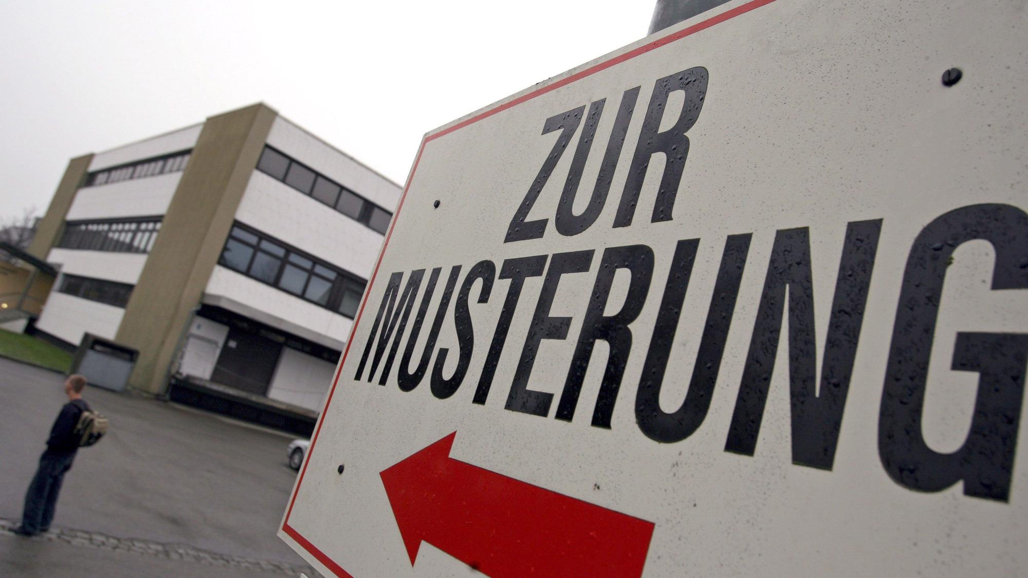 Ein Wehrpflichtiger steht unter einem Hinweisschild mit der Aufschrift „Zur Musterung“ vor dem Kreiswehrersatzamt.