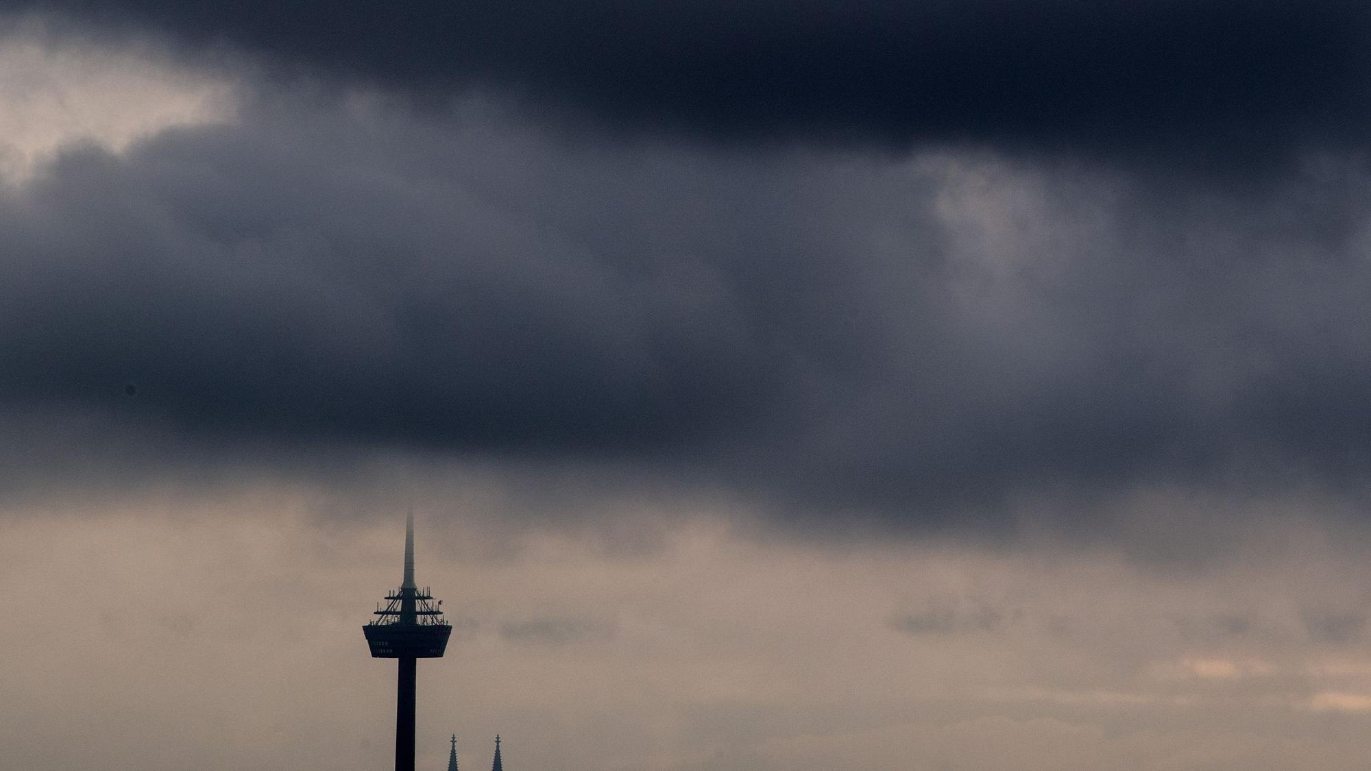 Dunkle Wolken ziehen über den Kölner Fernsehturm „Colonius“ hinweg