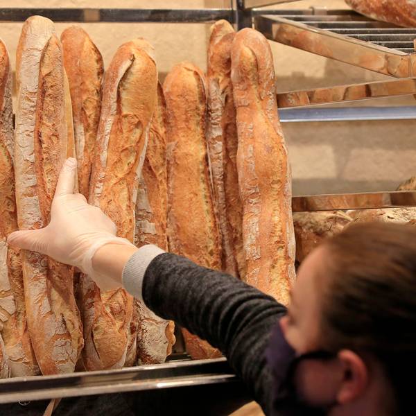 Eine Verkäuferin nimmt ein Baguette in einer Bäckerei.