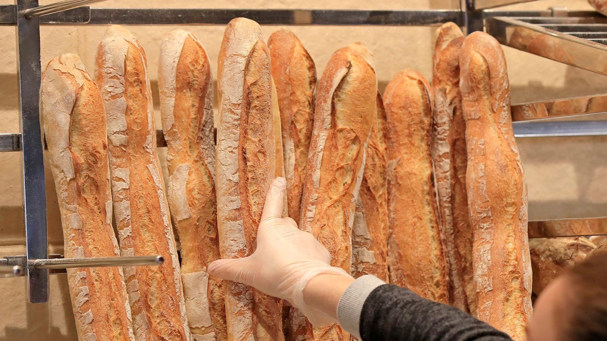 Eine Verkäuferin nimmt ein Baguette in einer Bäckerei.