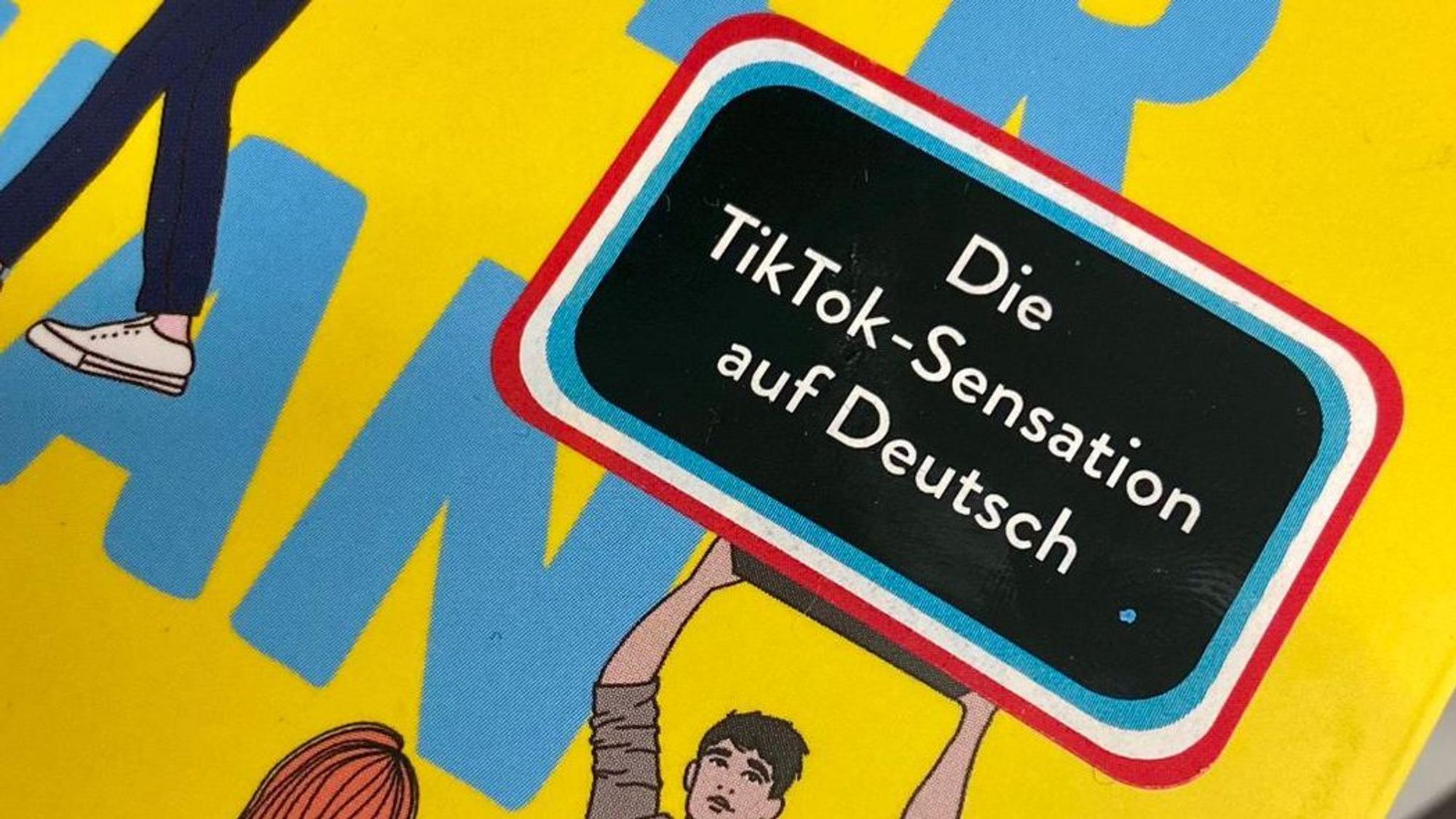 Auf einem Buch klebt ein Aufkleber mit der Aufschrift „Die TikTok-Sensation auf Deutsch“.