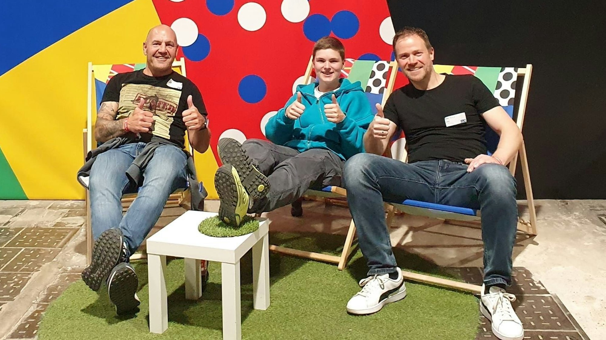 Das Bild zeigt die drei freiwilligen Helfer, wie sie in einem Liegestuhl sitzen.