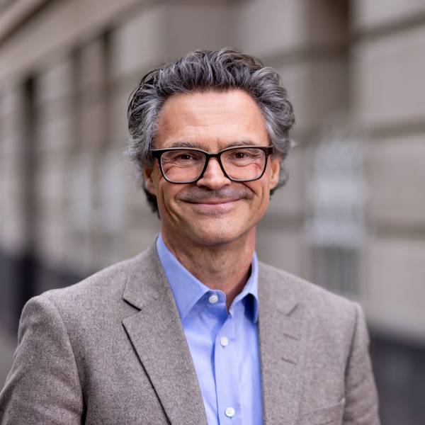Professor Dr. Rolf Schwartmann trägt einen grauen Anzug und lächelt
